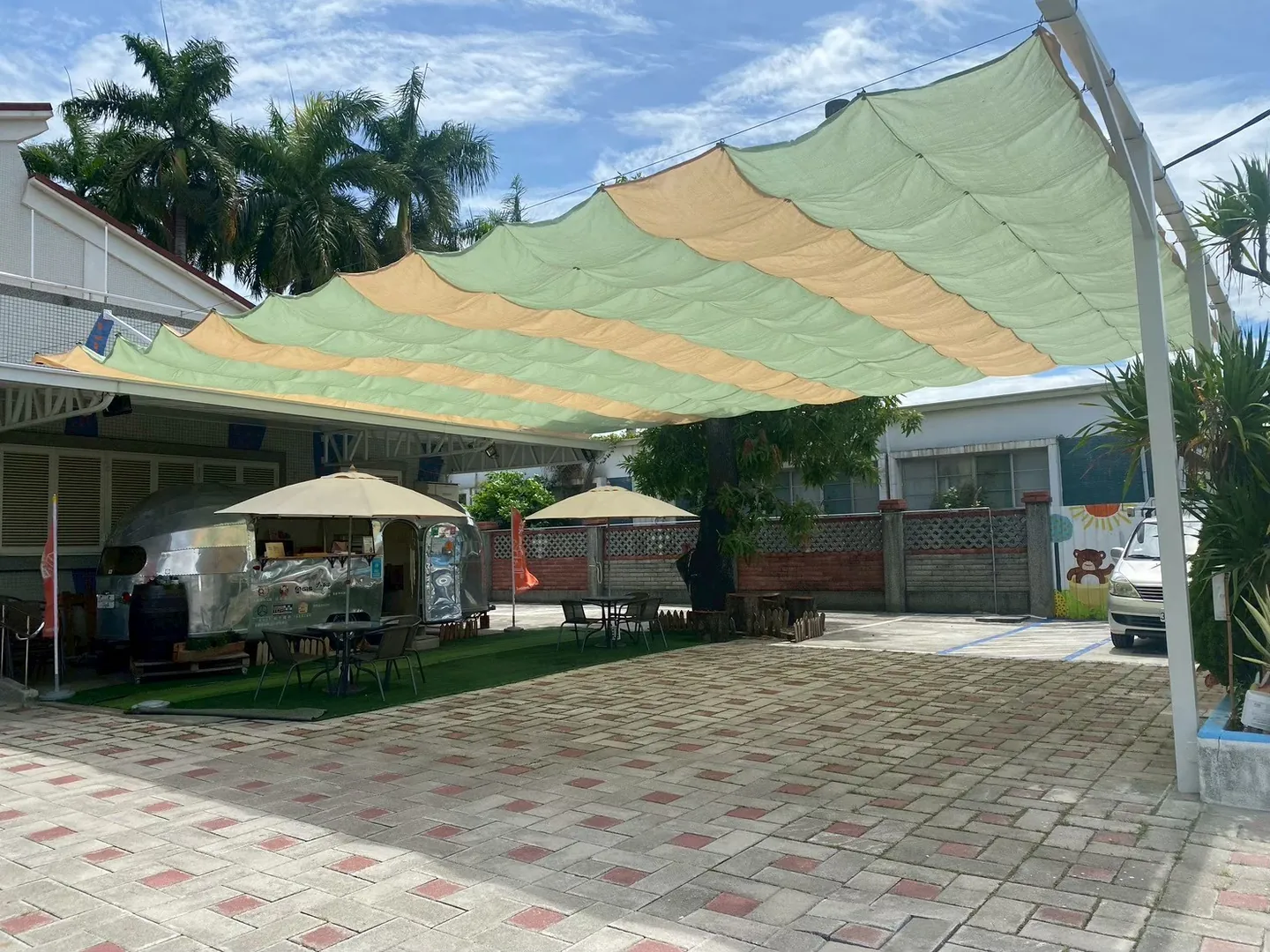 淺綠與米黃色活動式遮陽網展開於庭院上方,下方保留座席與開放空間