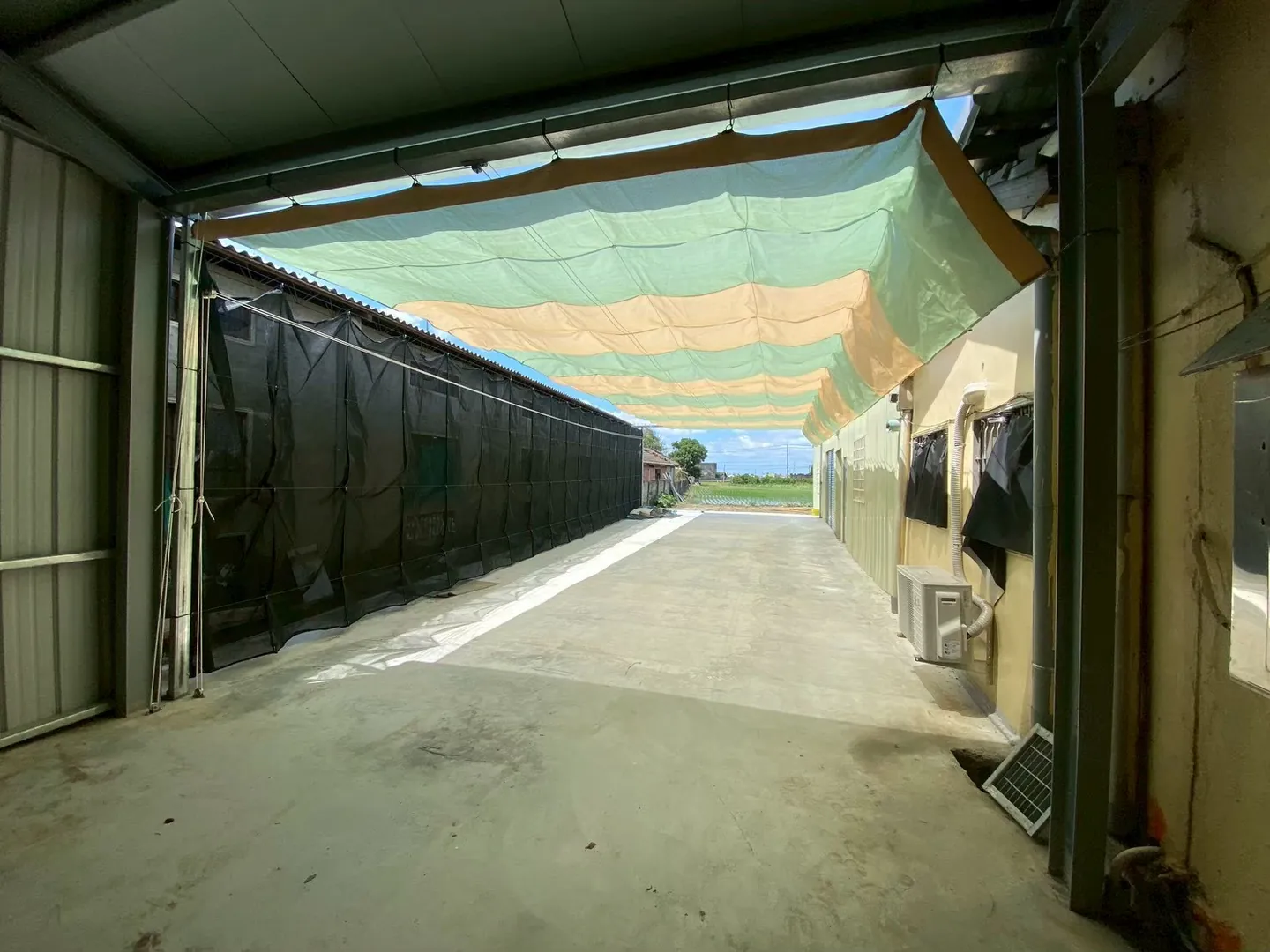 淺綠與米黃色活動式遮陽網沿兩棟建築之間的通道展開
